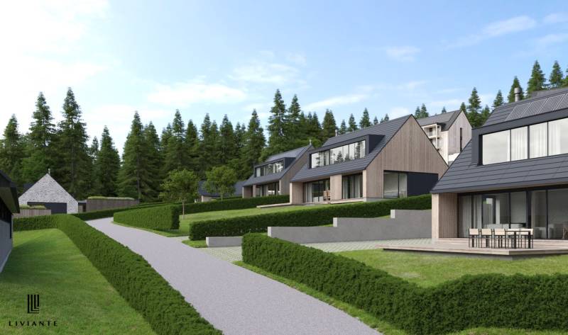 Development plots in Tajov with modern houses surrounded by forest and greenery.