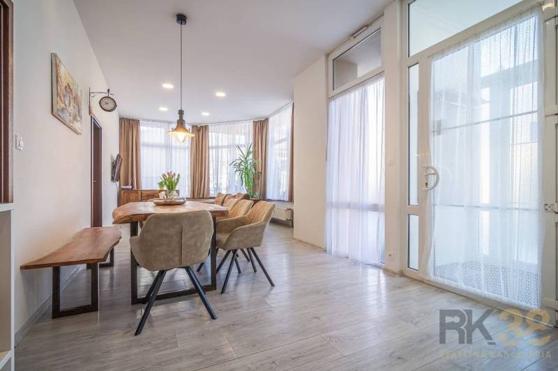 A dining room with large windows, comfortable chairs, a wooden table, interior on Hviezdoslavova Street.