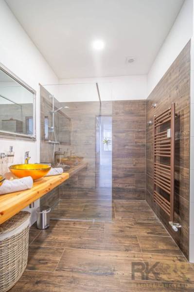 Bathroom with a spacious shower, a sink on a wooden countertop, and a floor with a wooden decor.