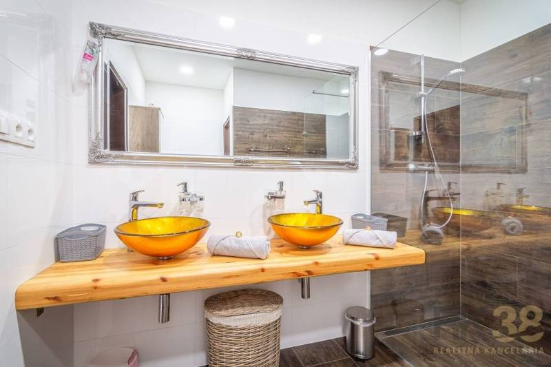 Bathroom on Hviezdoslavova Street with a wooden sink and glass bowls in a 4-room apartment.