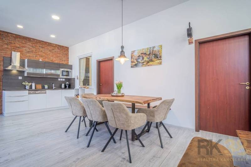 Dining room in a 4-room apartment, Hviezdoslavova Street; elegant wooden table and modern kitchen.