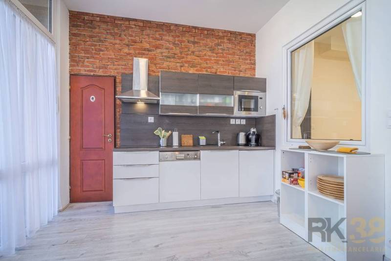 Kitchen unit with brick cladding and wooden decor flooring in commercial premises.