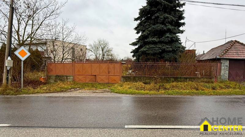 The path runs alongside residential plots in Pribeta, surrounded by trees and a gate.