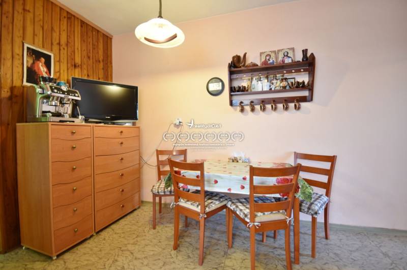A kitchen in a family house with wooden cabinets, a table with chairs, and a television.
