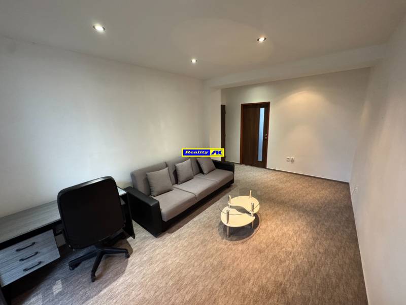 Living room with a sofa and a table in a 2-room apartment, with a carpet on the floor.