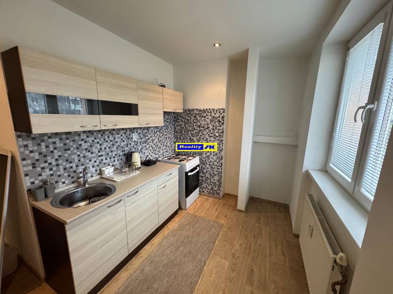 A kitchen in a 2-room apartment with a modern kitchen unit and a floor with a wooden decor.