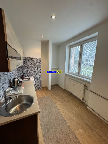 A kitchen in a 2-room apartment with a wooden decor floor and mosaic tiles.