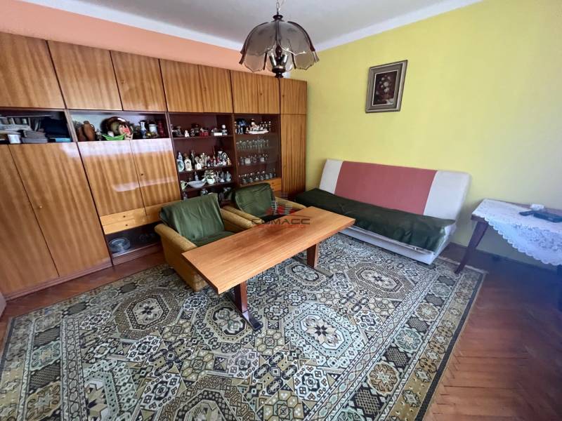 Living room in a family house with furniture, carpet, and a painting on the wall.