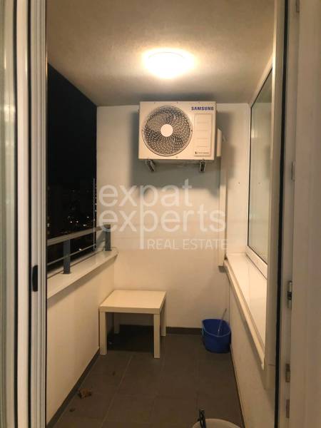 Balcony in a 2-room apartment with air conditioning, a table, and a cleaning bucket.