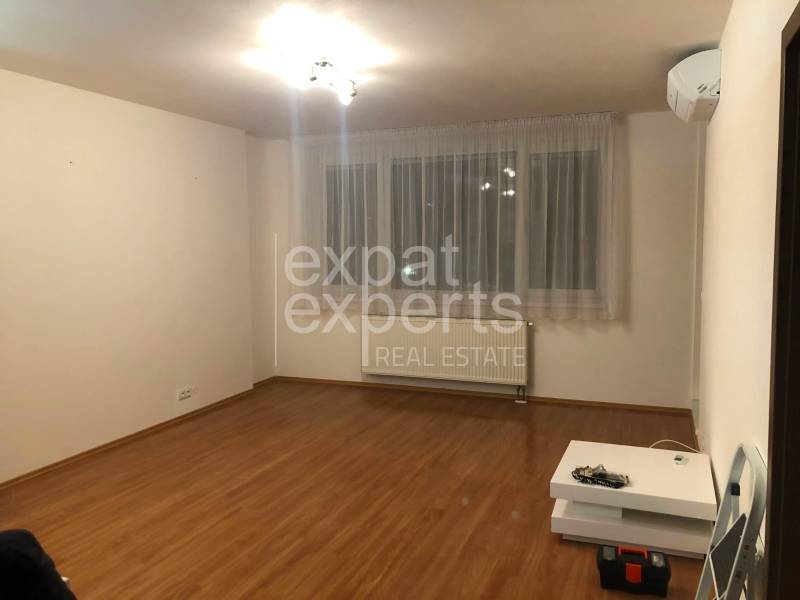 Living room in a two-room apartment with a wooden decor floor and air conditioning.
