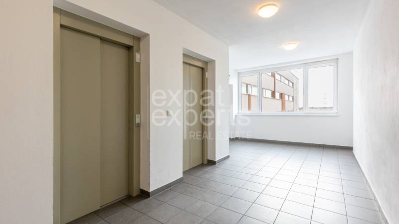 Hallway with elevators and tiled floor in a 2-room apartment.