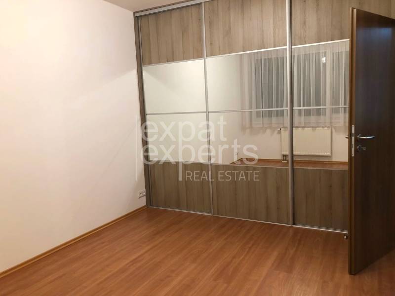 A room in a 2-room apartment with a wooden decor floor and a built-in wardrobe.