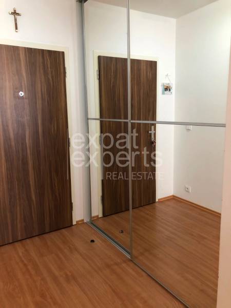 A hallway in a 2-room apartment with a wooden decor floor and a mirrored wardrobe.