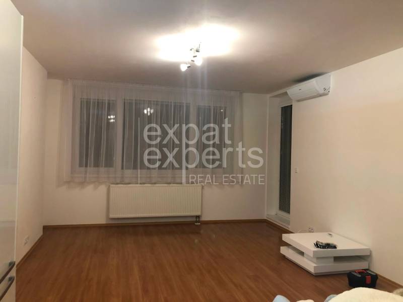 Living room with wood-patterned flooring and air conditioning in a 2-room apartment.