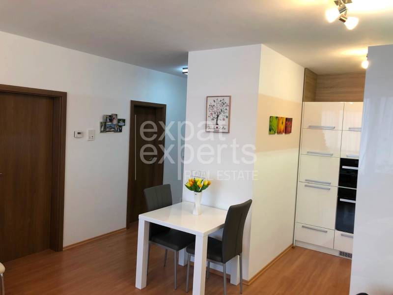 A dining table with two chairs and a floor with a wooden decor in a 2-room apartment.