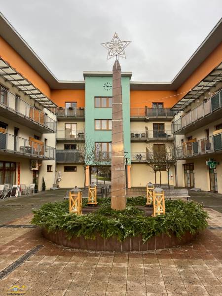 The courtyard in Oščadnica with a decorative column and modern apartments around.