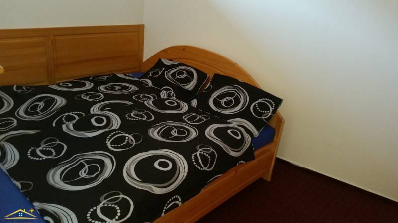 A double bed with a wooden headboard and black and white bedding in a holiday apartment.