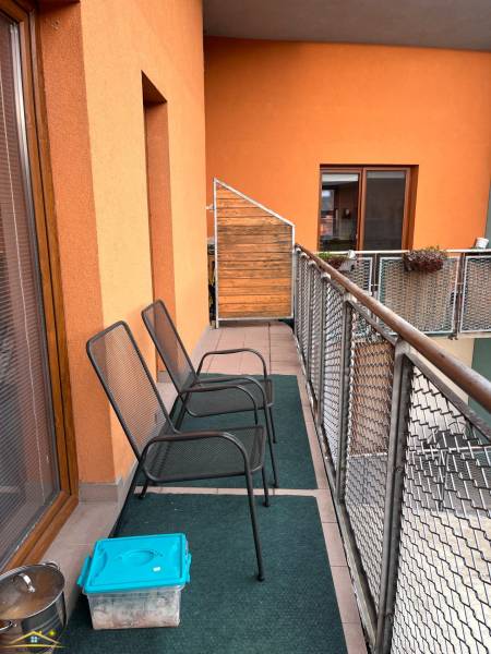 Balcony of a recreational apartment in Oščadnica with two metal chairs and glass doors.