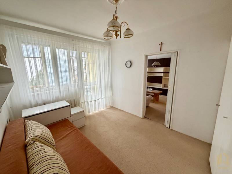 A room in a 3-room apartment with a bed, furniture, a large window, and curtains.