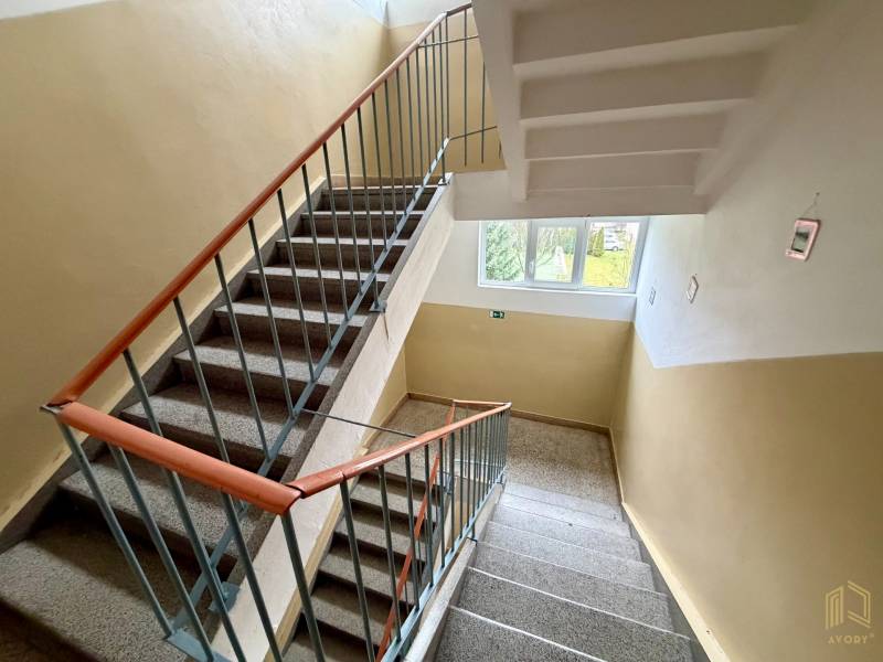 Apartment building staircase with windows and railing.