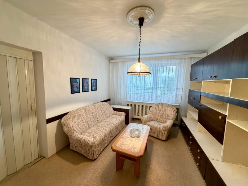 Living room in a three-room apartment with a sofa, an armchair, and furniture, soft lighting.