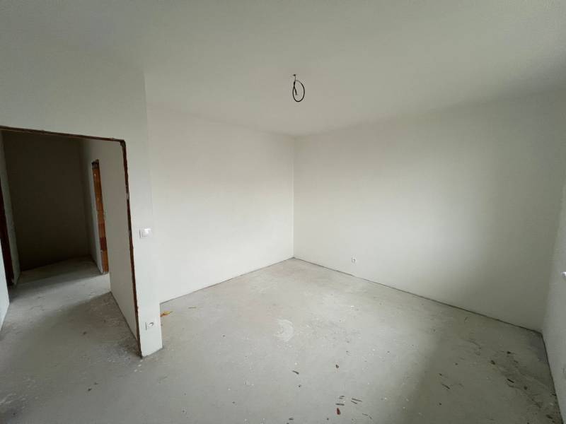 A room in a family house with white walls, concrete floor, unfurnished.