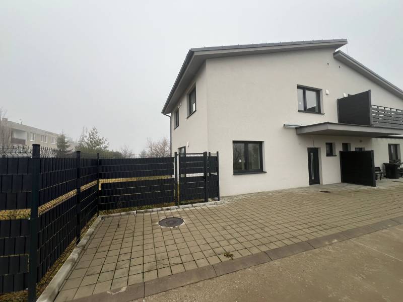 A family house in Plavecký Mikuláš with a paved courtyard and a black fence in the yard.