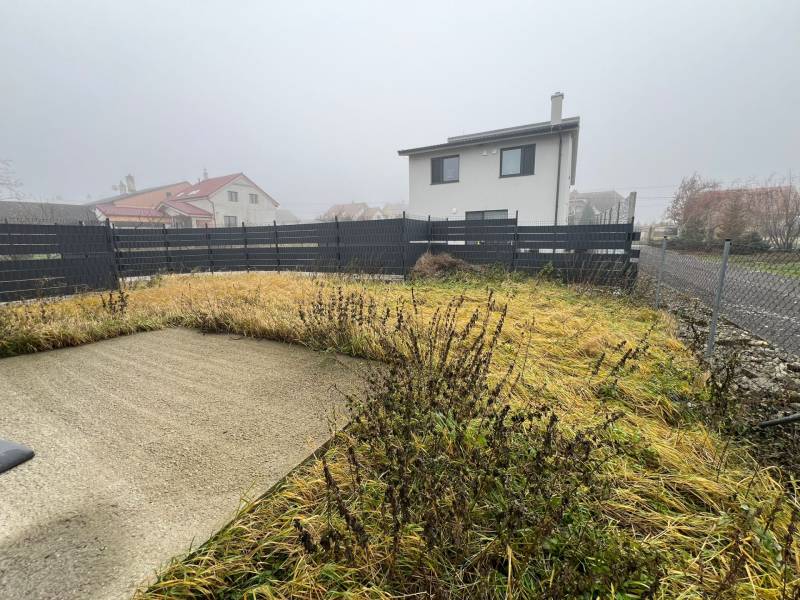 The courtyard of a family house in Plavecký Mikuláš with tall grass and a concrete area.