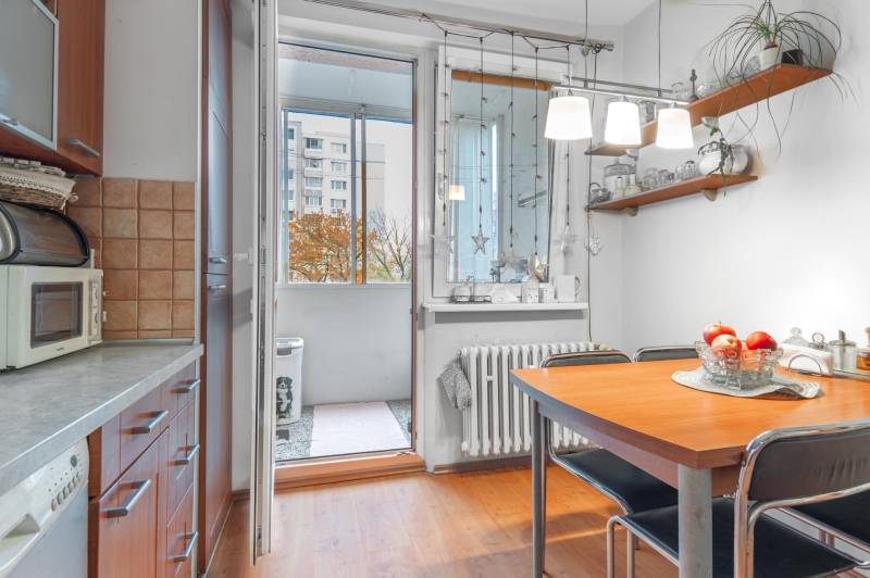Kitchen with dining table, wood-patterned floor, access to balcony, 4-room apartment.