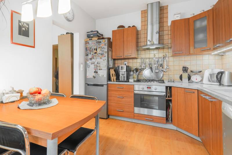A kitchen in a 4-room apartment with a wooden decor floor and wooden cabinets.