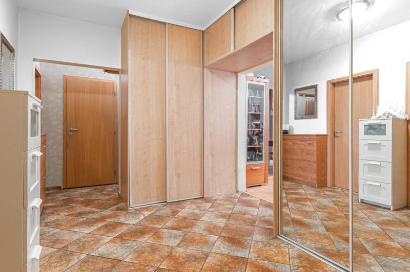 In the hallway of the 4-room apartment, there are built-in wardrobes and patterned tiles.