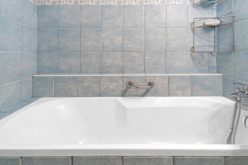 Blue bathroom with a bathtub and a holder in a 4-room apartment.
