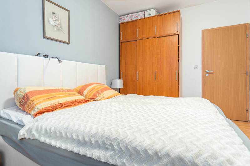 Bedroom in a 4-room apartment with a wooden wardrobe, a white headboard, and a picture on the wall.