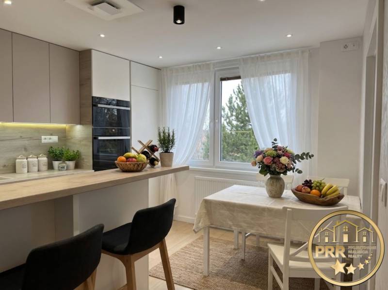 Bright kitchen in a 3-room apartment with a large window and a table, wood decor.