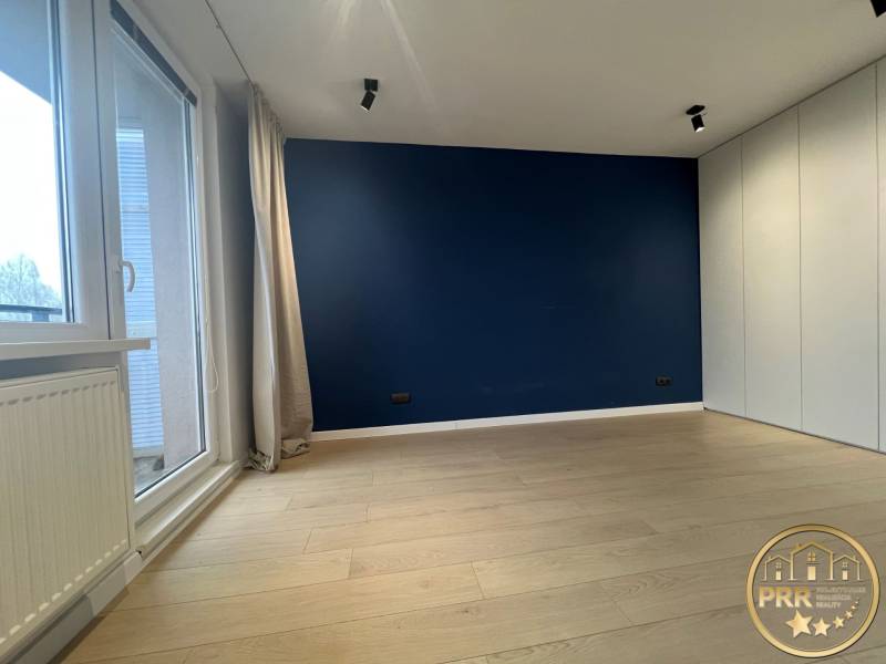 A room in a 3-room apartment with a blue wall, a floor with a wood decor, and balcony doors.