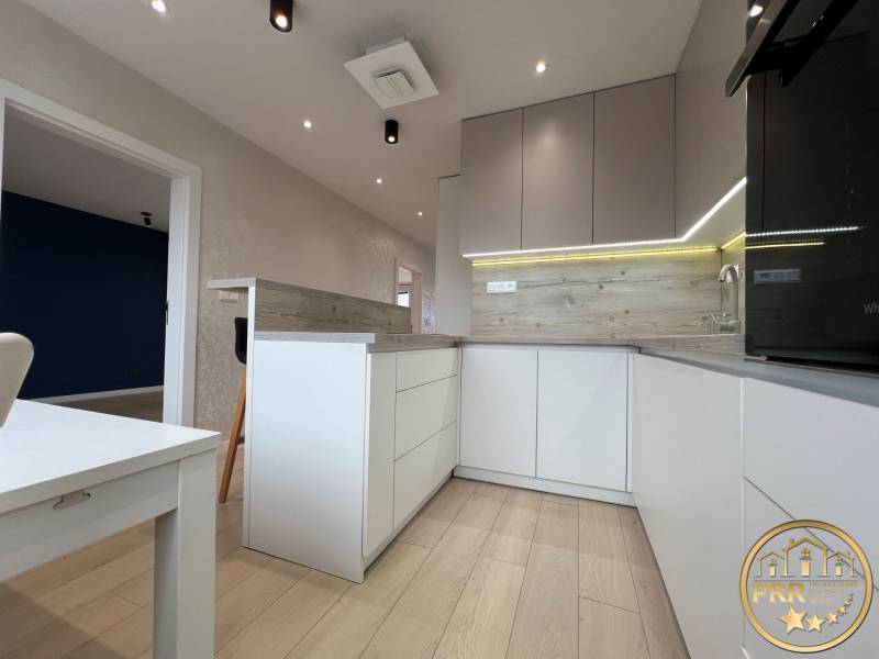 A kitchen in a 3-room apartment with a wooden decor floor and modern lighting.