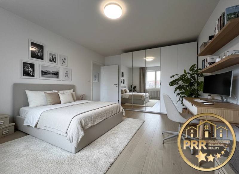 Bedroom in a 3-room apartment with wood-patterned flooring, a mirrored wardrobe, and a desk.