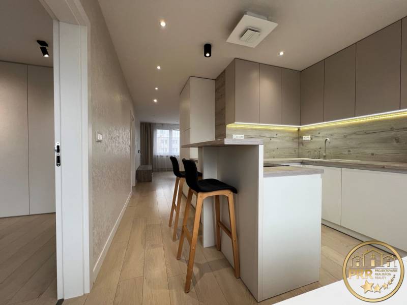 A kitchen with an island and a wooden decor floor in a 3-room apartment.