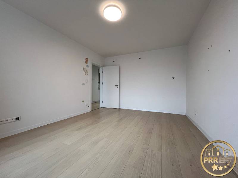 A room with a wooden decor floor in a 3-room apartment, minimalist white walls.