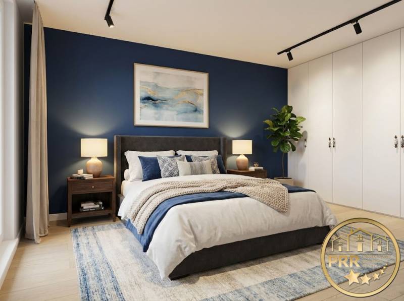 A bedroom in a 3-room apartment with a blue wall, white cabinets, a plant, and a floor with a wood decor.