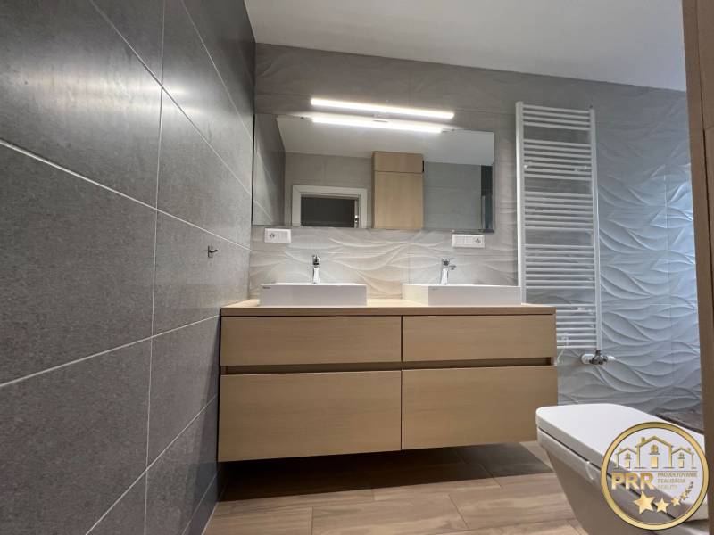 A bathroom in a 3-room apartment with a double sink, gray tiles, and wooden decor.
