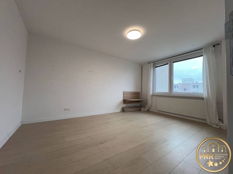 A room in a 3-room apartment with a wood-decor floor and a large window.