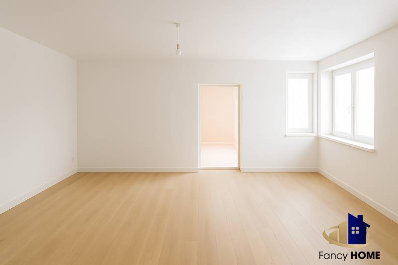 An empty room with white walls and a wood-patterned floor in a family house.