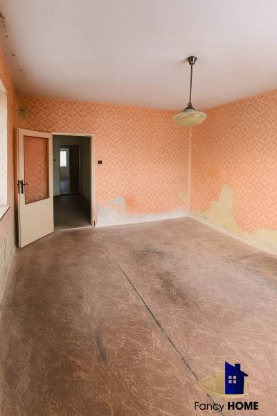 A room with wallpaper and a wood-patterned floor in a family house.