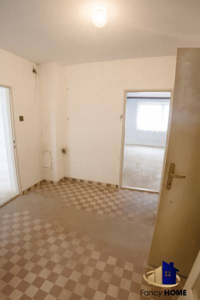 A view into the hallway of a family house with a tiled floor and white walls.