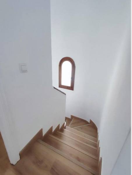 A staircase with a wooden floor decor and an arched window in a family house.