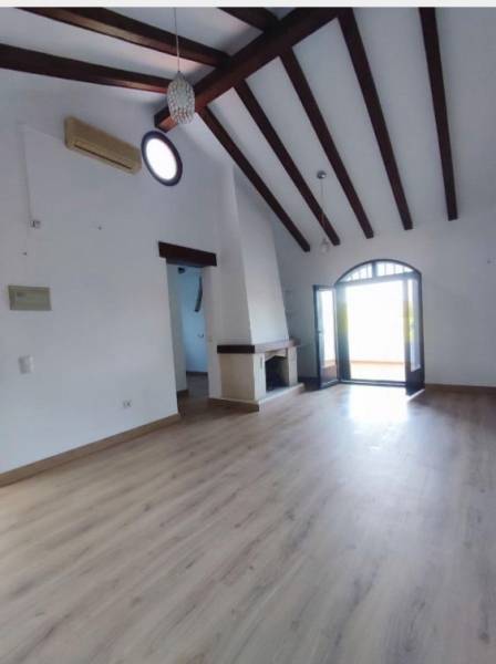 Living room in a family house with a high ceiling, fireplace, and wooden decor flooring.