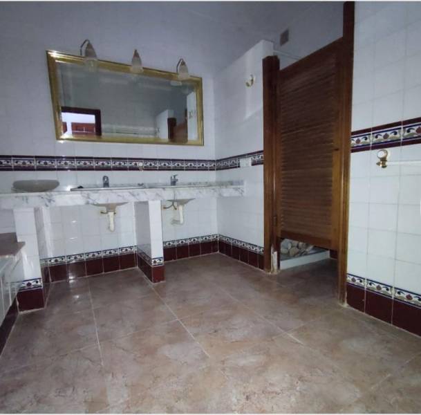 A bathroom in a family house with two sinks, a mirror, and a tiled wall.