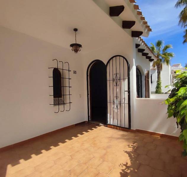 Entrance to a family house with tiles, wrought iron grilles, and a decorative lamp.
