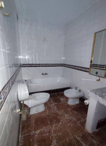 A bathroom in a family house with a bathtub, bidet, and a marble-patterned floor.